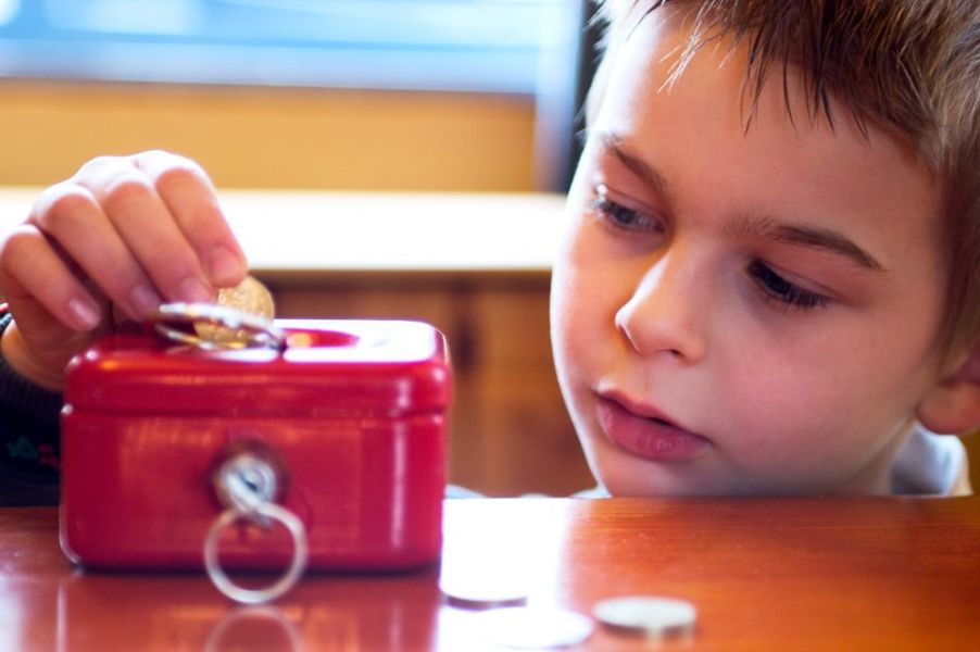 Editorial - boy putting money in a money box