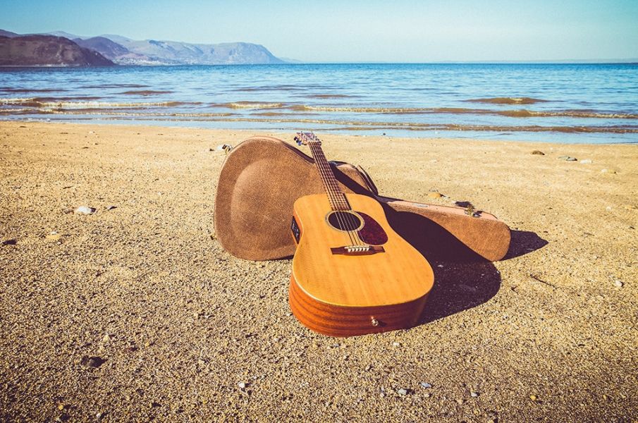 Editorial photo of an acoustic guitar on a beach